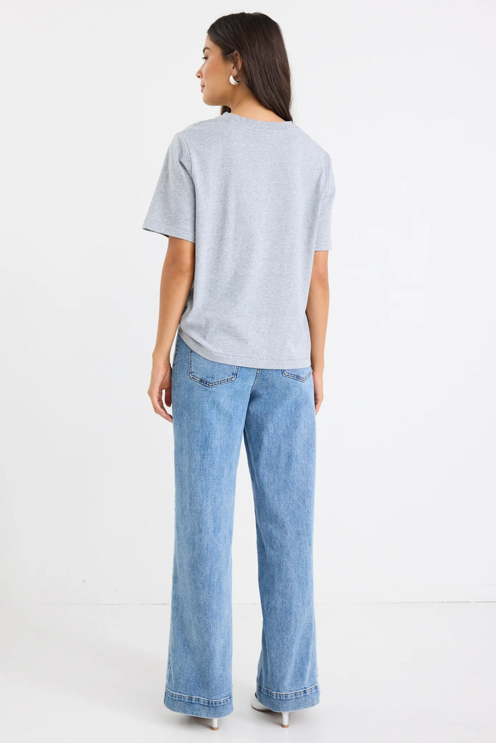 Woman wearing a light gray t-shirt and blue Zoey jeans on a white background