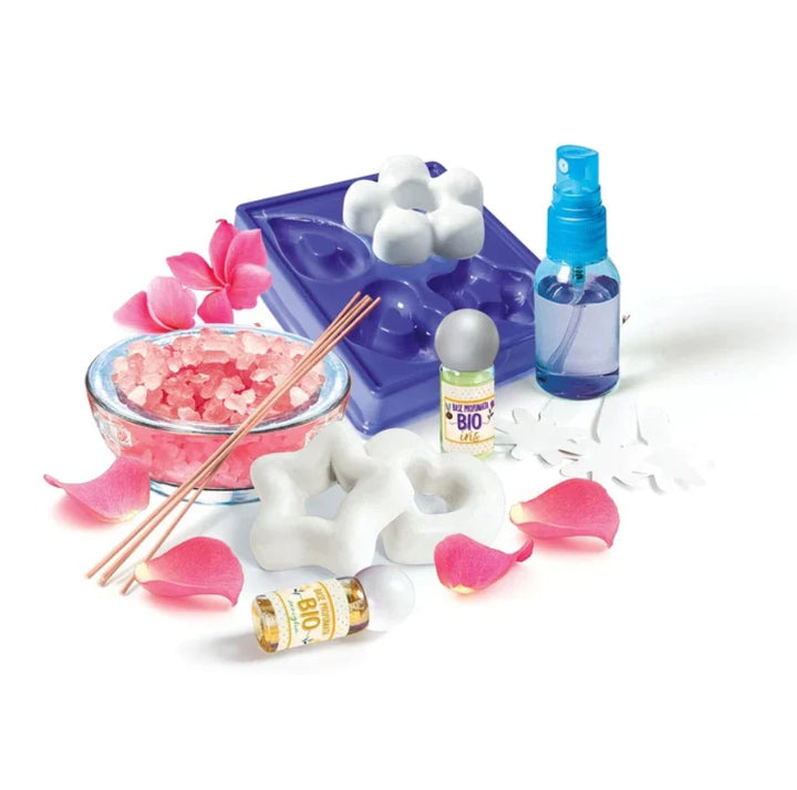 Assorted aromatherapy and spa products including a blue mold, pink flowers, and bottles on a white background.