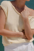 Person wearing a light-colored sleeveless top with a blurred background