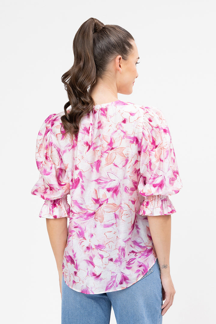 Woman wearing a pink floral blouse with blue jeans on a white background