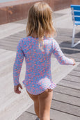 Child wearing a floral swimsuit on a wooden deck