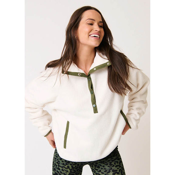 Woman wearing a cartel & willow white fleece Mattie pullover with green accents on a plain background