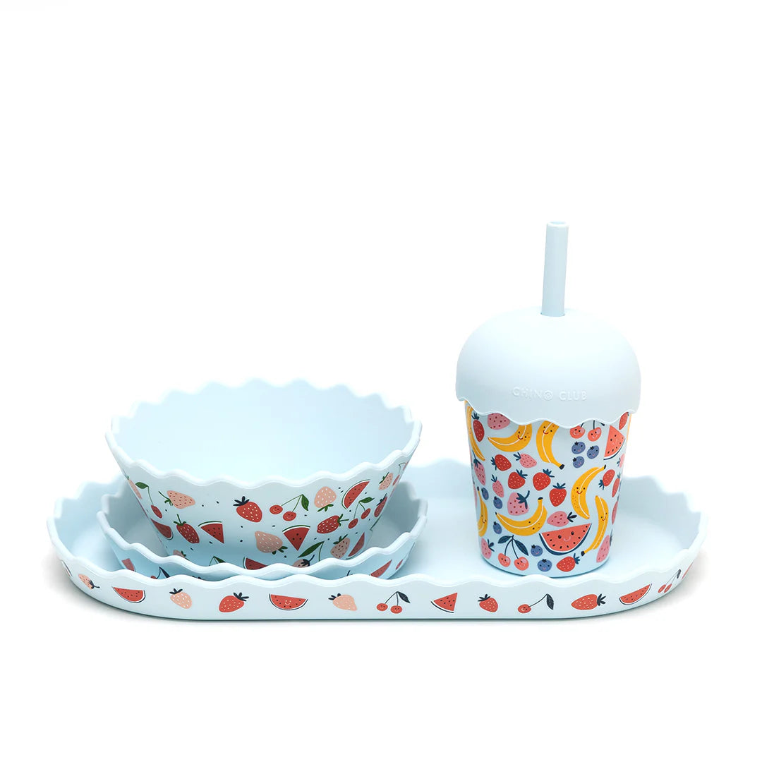 Set of children's tableware with a bowl, cup, and tray featuring fruit patterns on a white background.