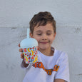 Child holding a colorful cup with a straw against a light gray wall