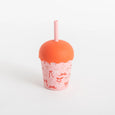 Pink tumbler with orange lid and straw on a white background