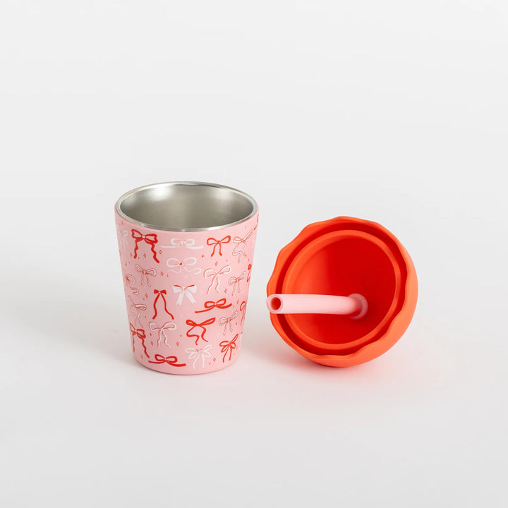 Pink stainless steel cup with red lid and straw on a white background