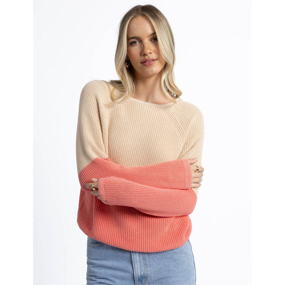 Woman wearing a two-tone sweater with beige and coral colors on a white background