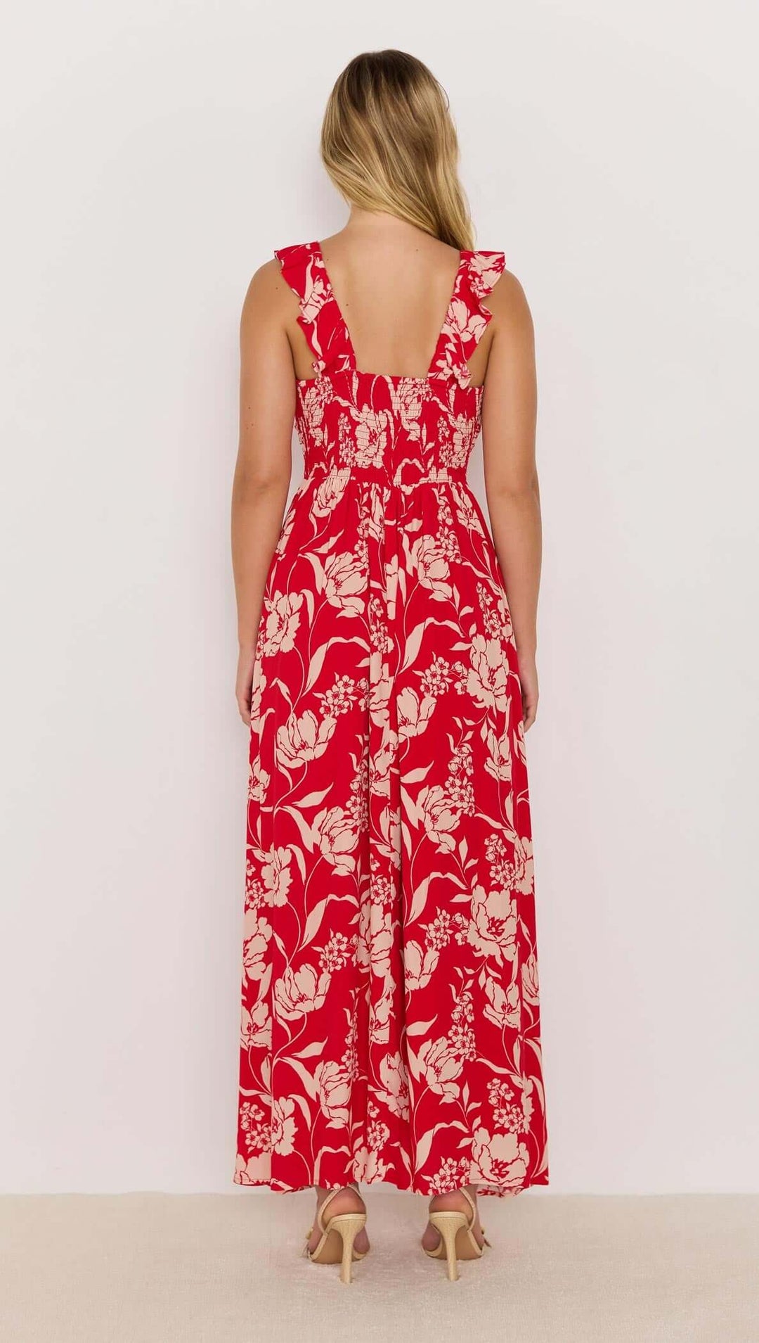 Woman wearing a red floral jumpsuit on a white background