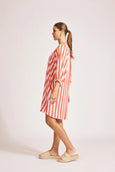 Woman wearing a red and white striped eb and ive dress on a plain background