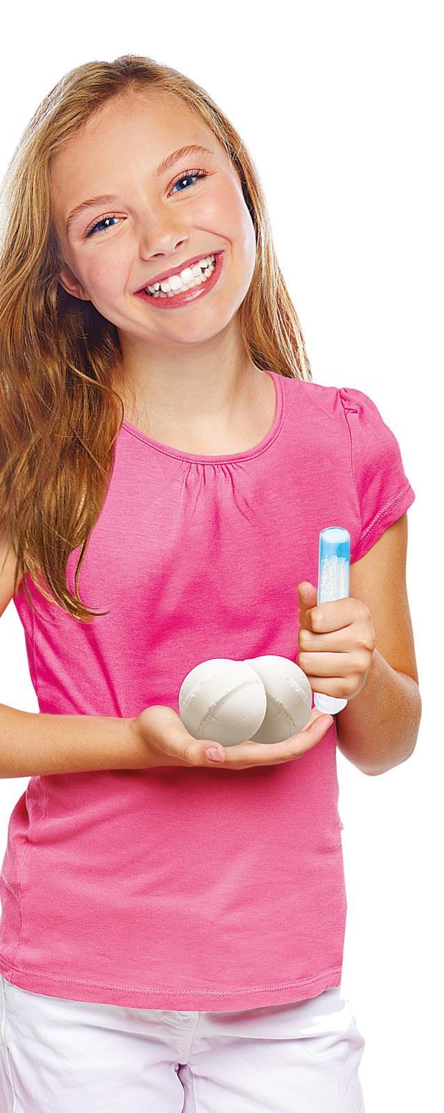 Young girl in a pink shirt holding a white ball and a blue and white container on a white background