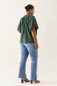 Person wearing a green isle of mine top and blue jeans on a white background