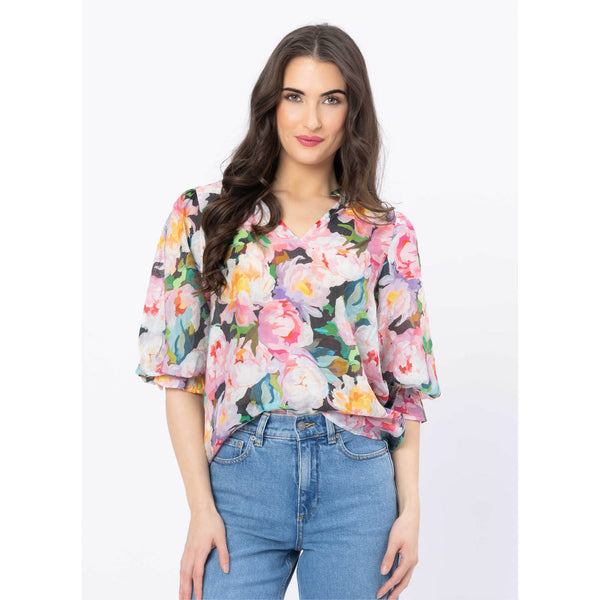 Woman wearing a colorful floral blouse and blue jeans on a white background