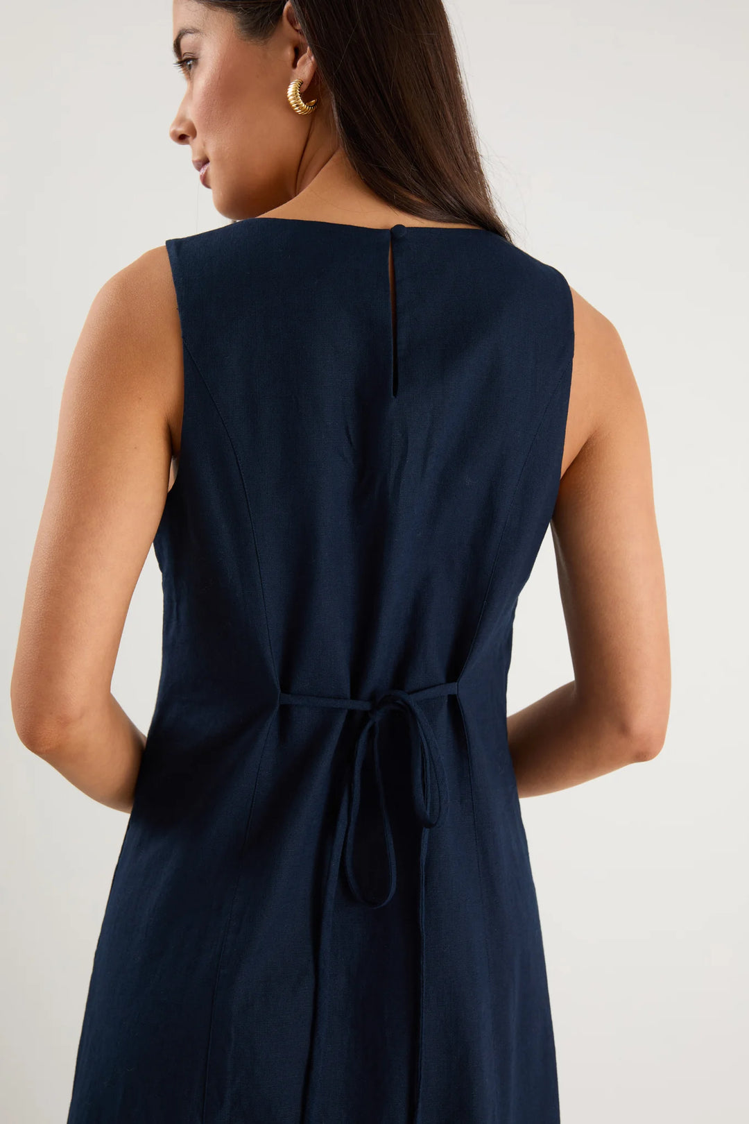 Navy blue sleeveless dress with a tie detail on a plain background