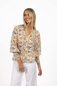 Woman wearing a floral blouse and white pants on a white background