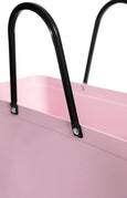Close-up of a pink plastic bag with black handles on a white background