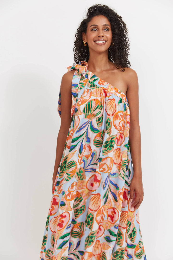 Woman wearing a colorful Haven floral one-shoulder dress on a white background