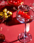 Cocktail glass with red cherries on a red background