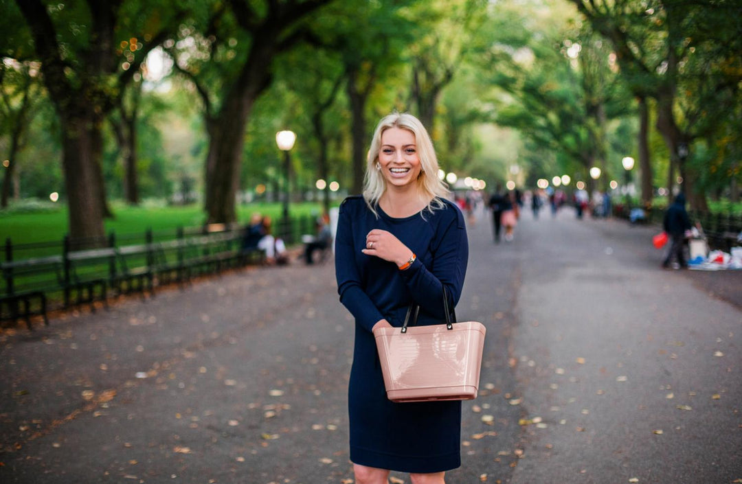 Woman holding a pink handbag in a park setting