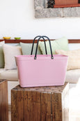Pink tote bag with black handles on a wooden block in a living room setting