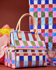 Colorful checkered cooler bag with PU handle on a patterned background