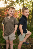 Two young boys standing outdoors with a natural background