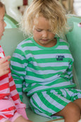 Child wearing a green and white striped outfit with 'ATHL CLUB' logo on a light green couch.