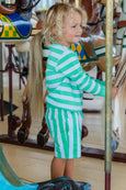 Child in green and white striped outfit on a carousel