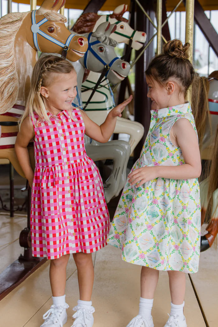 Two young girls in Milky dresses standing next to a carousel with horses.