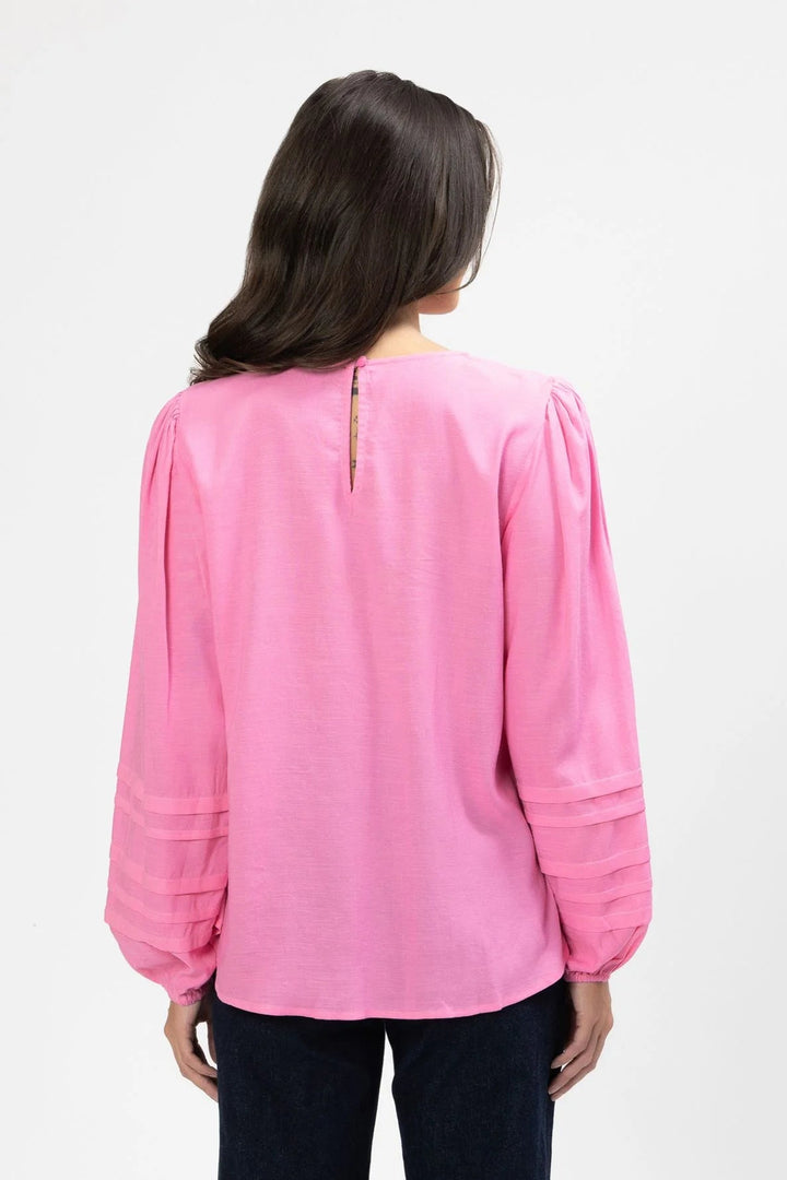 Person wearing a pink Milly blouse with long sleeves on a white background