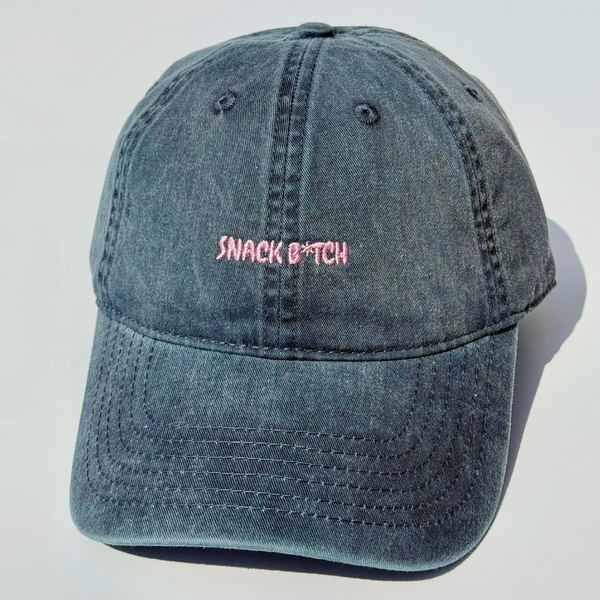 Blue denim cap with pink text on a light gray background