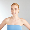 Woman wearing a strapless blue top against a plain background