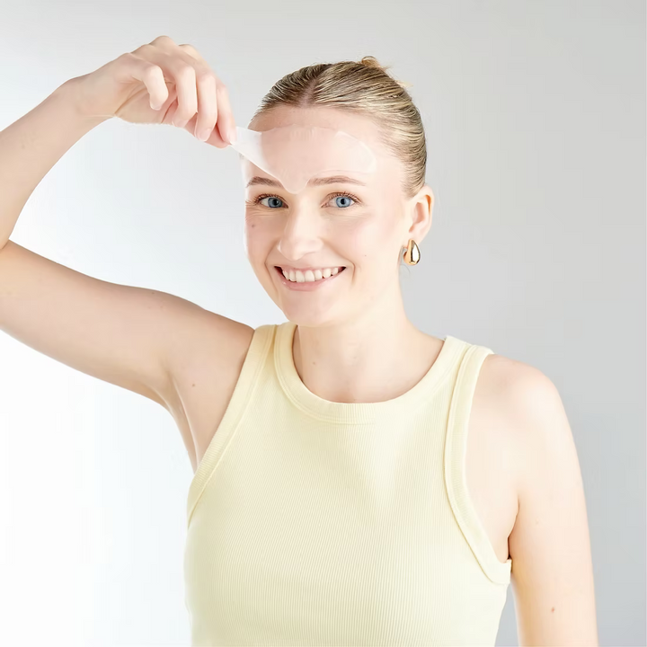 Woman applying sunscreen on her face with a white background