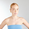 Woman wearing a blue strapless top with a plain background