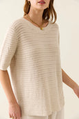 Woman wearing a beige crochet isle of mine top against a plain background
