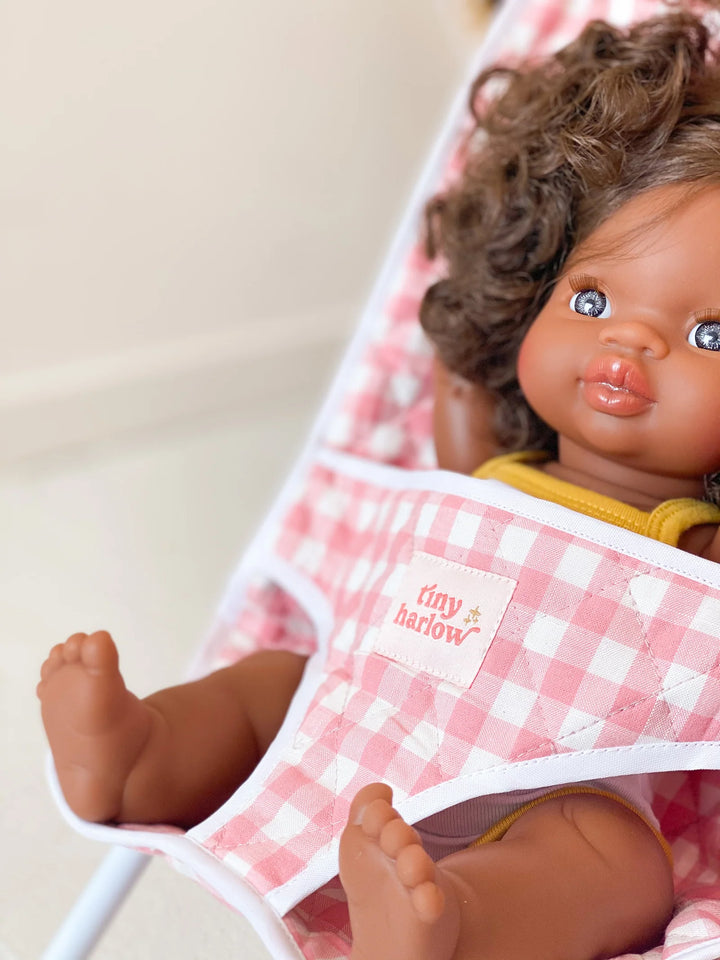 Baby doll close up in a pink and white gingham tiny harlow dolls stroller. w