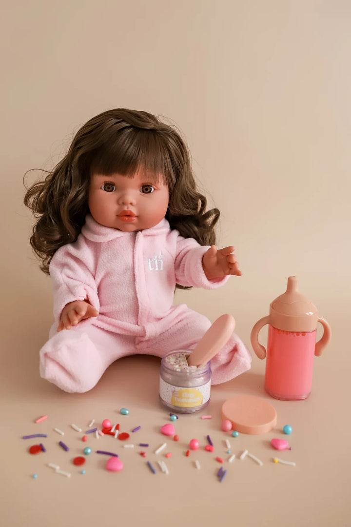 Doll in pink outfit with accessories on a beige background