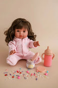 Doll in pink outfit with accessories on a beige background