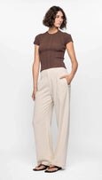 Woman wearing a brown top and beige pants on a white background