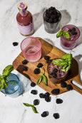 Garnished cocktails with blackberries on a marble surface